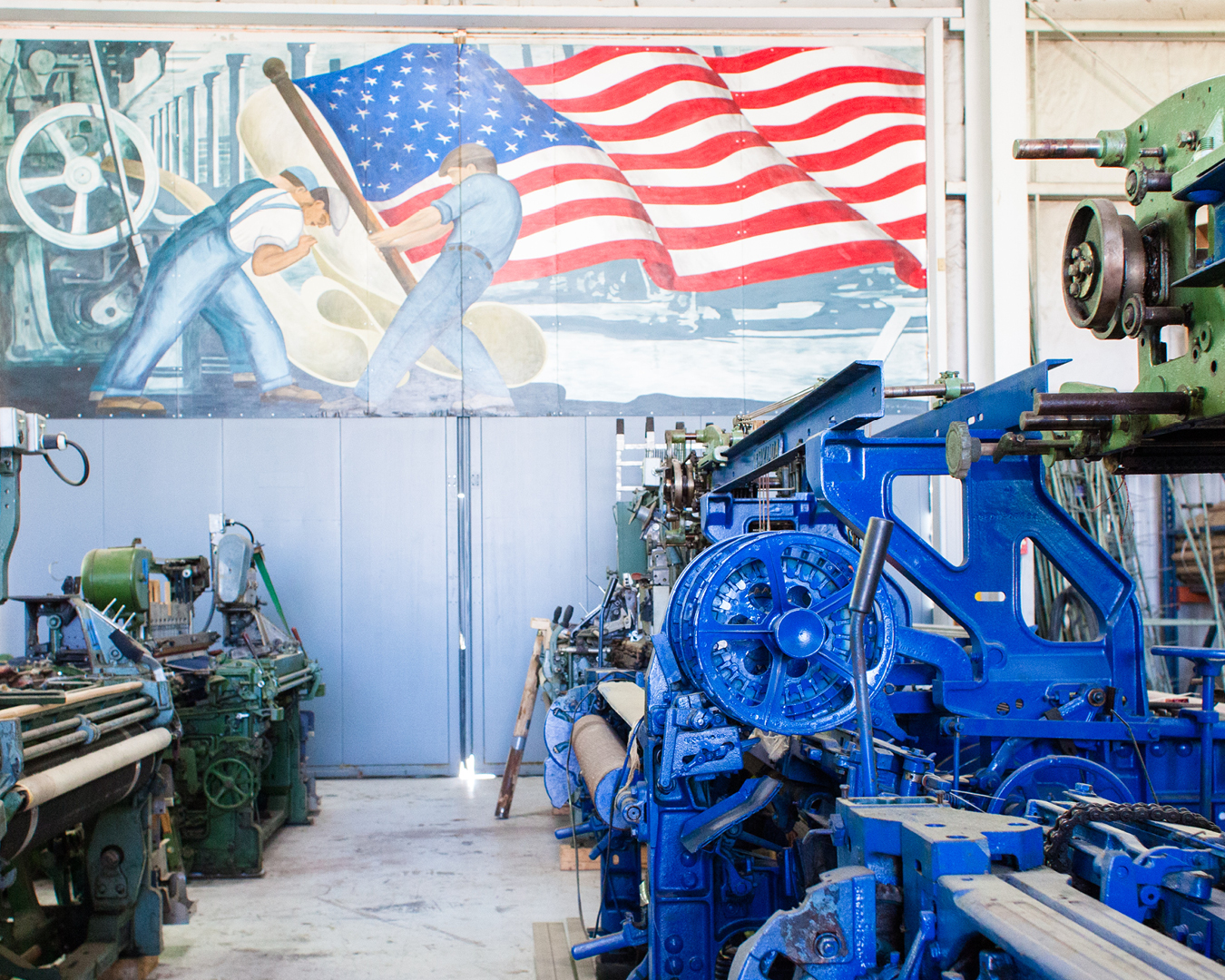 color-photograph-green-and-blue-mechanical-looms-below-large-american-flag-mural