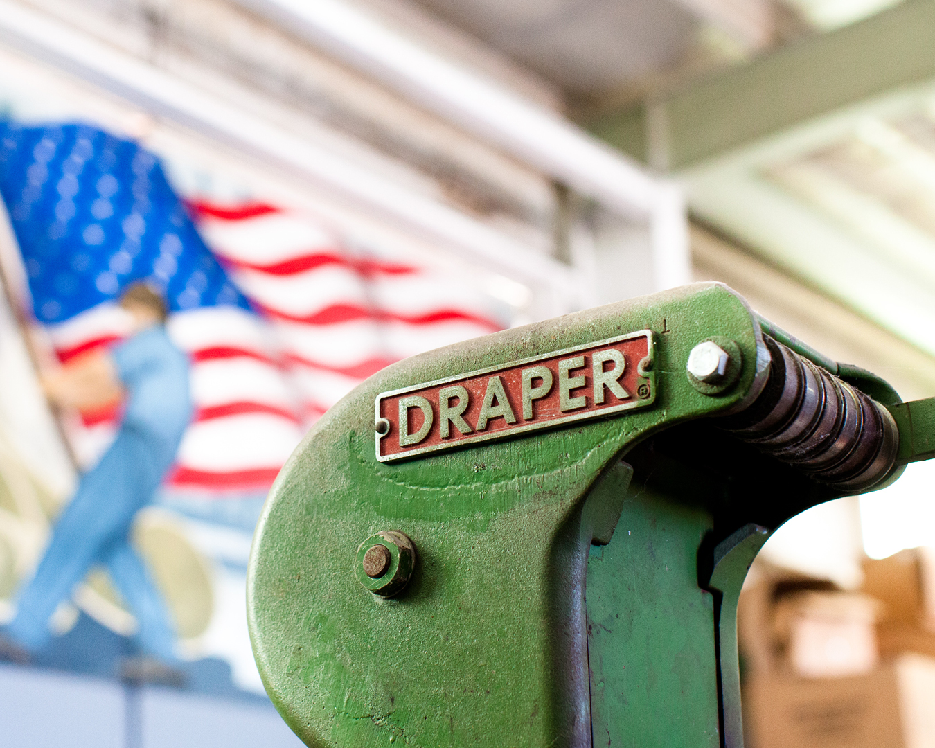 photograph-red-and-gold-industrial-nameplate-Draper-on-green-loom-american-flag-mural-in-background