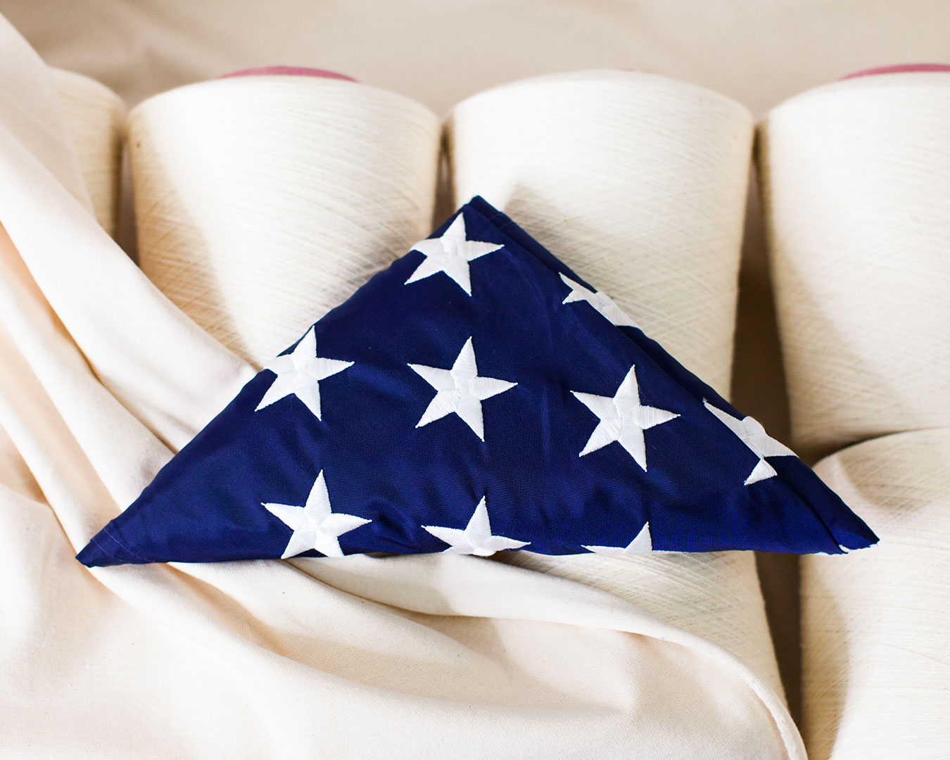 photograph-overhead-of-us-military-flag-folded-triangle-on-white-cones-of-yarn-and-fabric