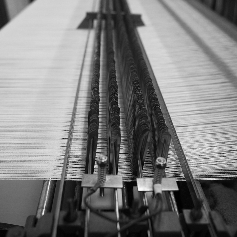 black-and-white-photograph-of-hundreds-of-yarn-ends-moving-through-loom-needles-in-the-middle