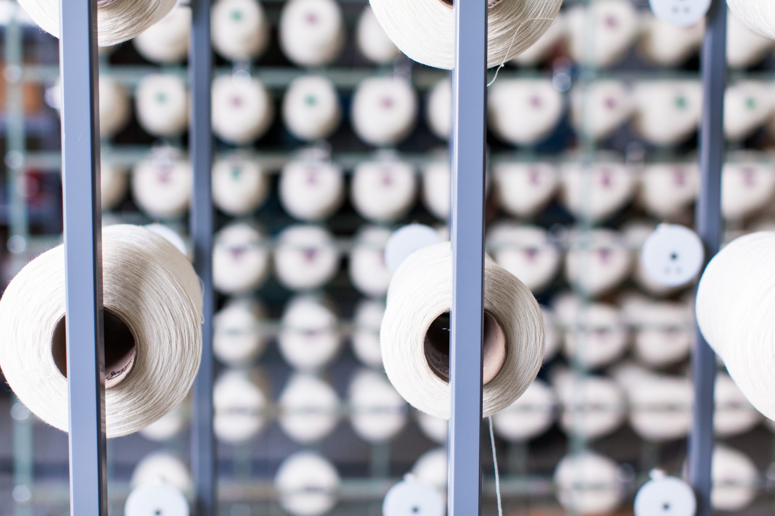 photograph of many white cones of cotton yarn on restored and modified textile frame