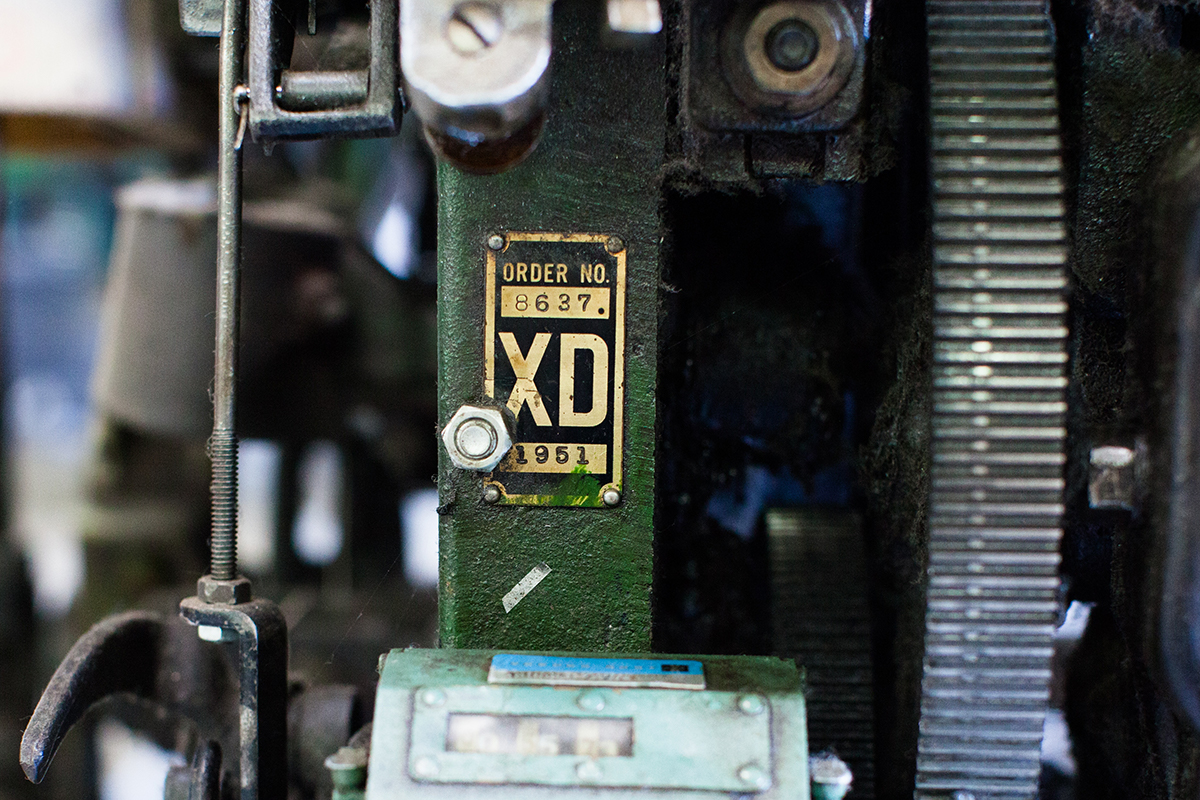 color photograph showing a green draper XD industrial shuttle loom nameplate near machine gears