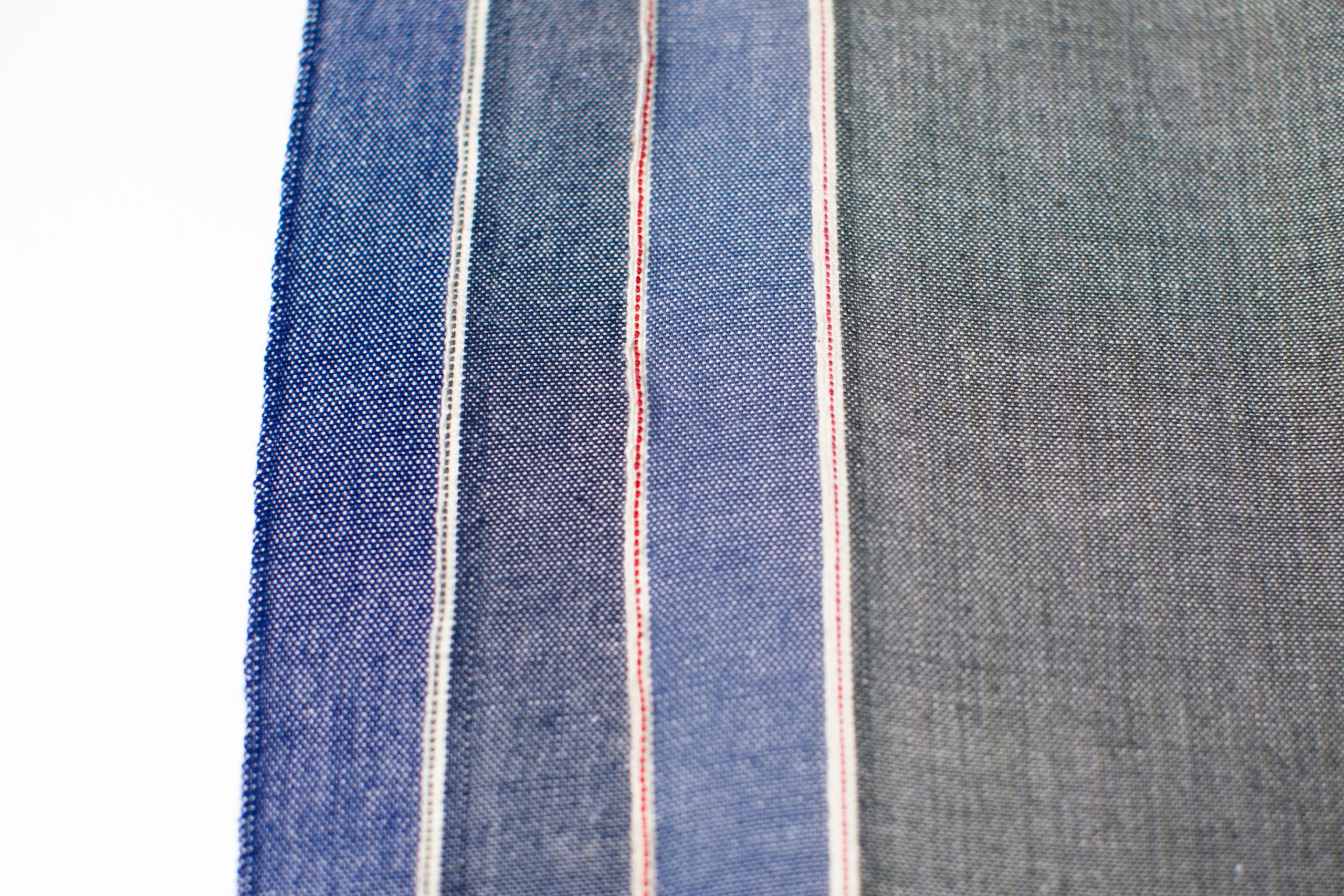 overhead-photograph-of-four-overlapping-blue-and-black-overhead photograph of four overlapping blue and black selvedge textiles with red or blue ticker ID