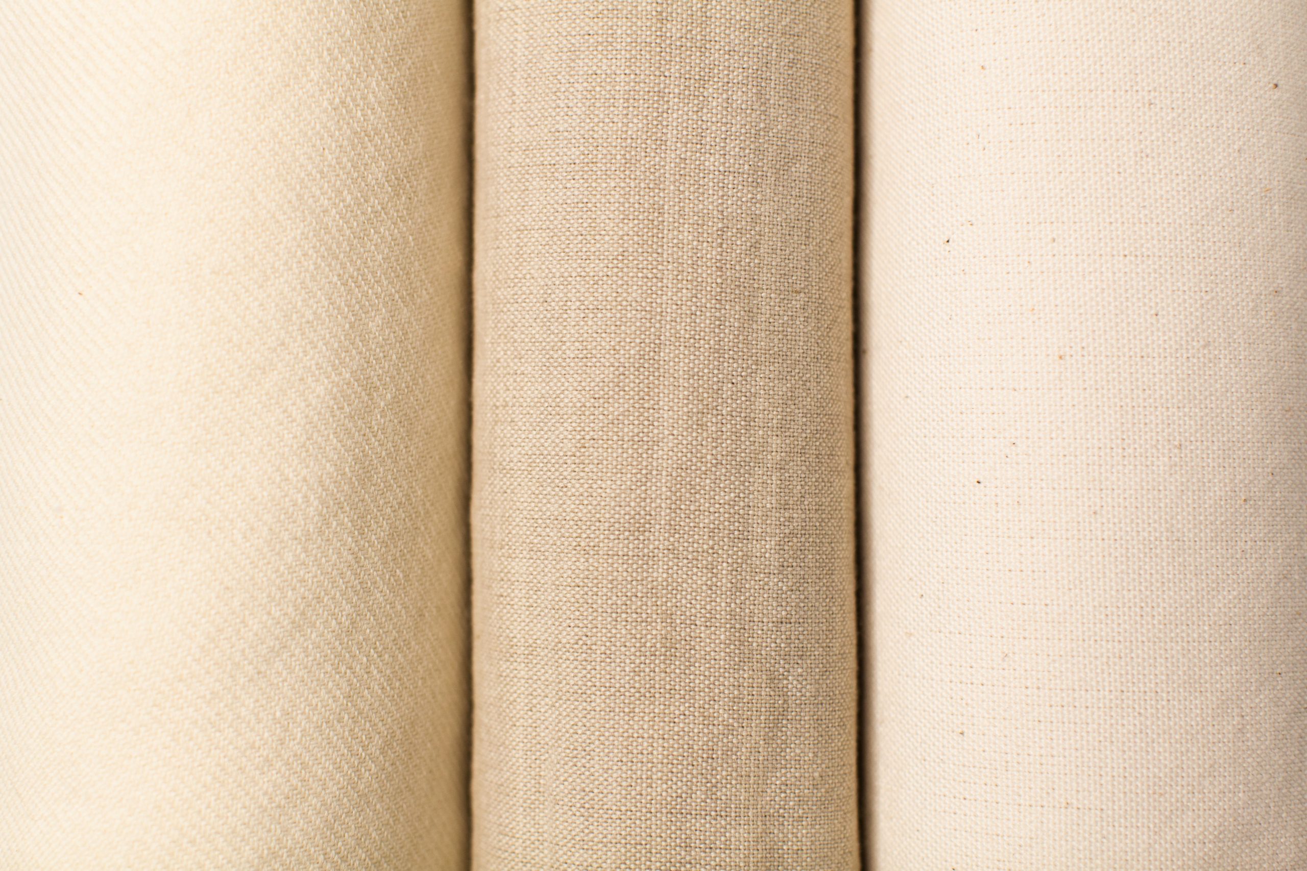 color photograph of three different heritage textiles from a creamy off white wool twill to tan and white cotton plain weaves