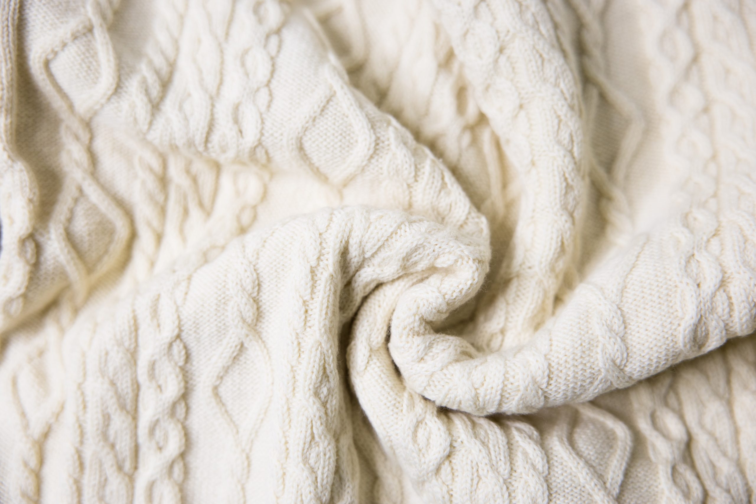 Close up detailed photograph of oyster white wool, Multi-cable fine knit Wholegarment sample