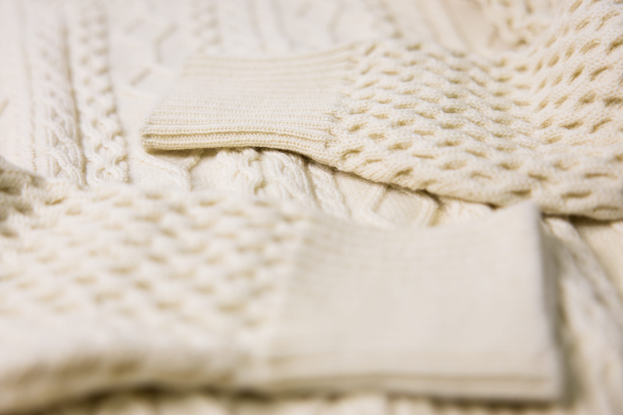 Close up detailed photograph of oyster white wool, Multi-cable fine knit Wholegarment sweater